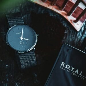 Close-up of a luxury wristwatch paired with Royal eau de toilette on a textured surface.